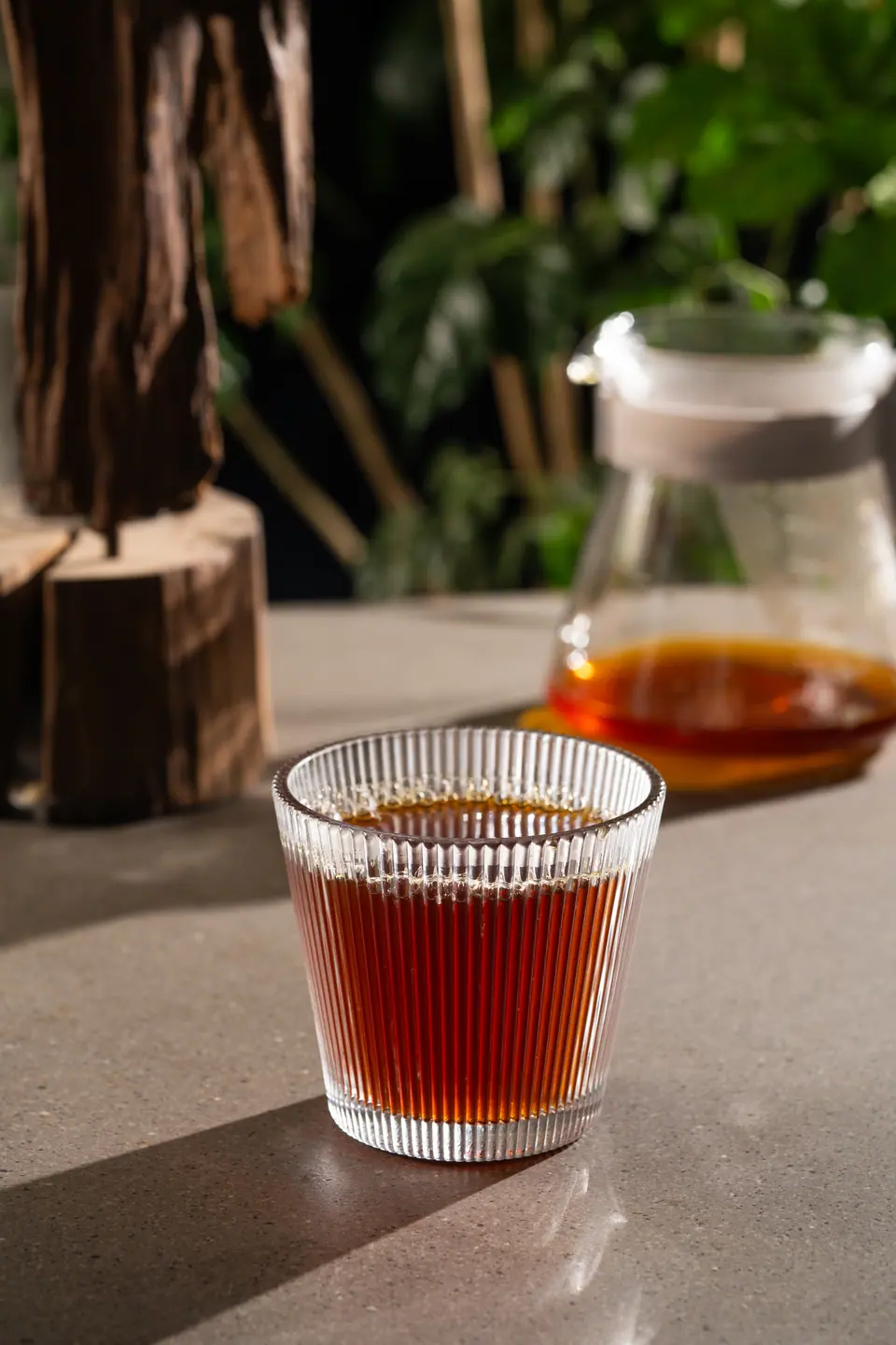 Cold brew in a ribbed glass beside a carafe